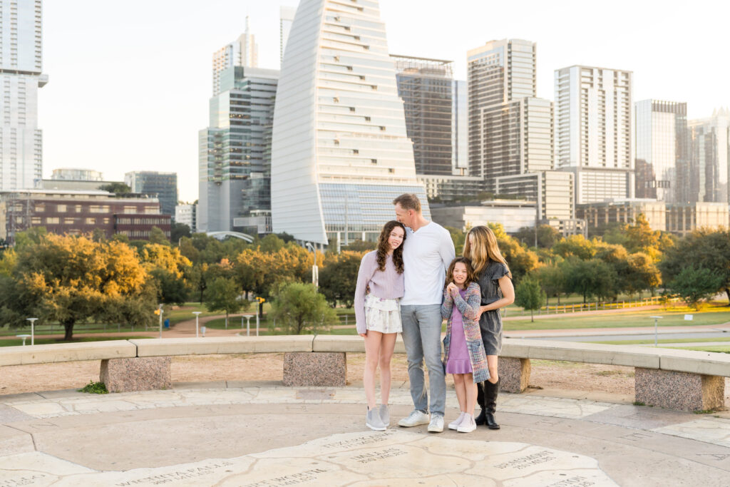 A father kissing his daughter's head and a mother holding onto her daughter during their family photo session.