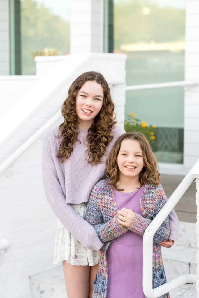 Two sisters standing on white steps in downtown Austin.