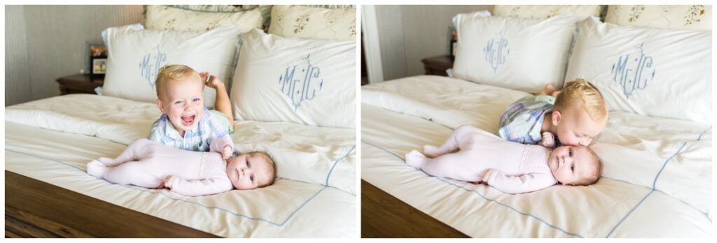 Big brother holding his new sister while sitting on mom and dad's bed during a newborn photographer session.