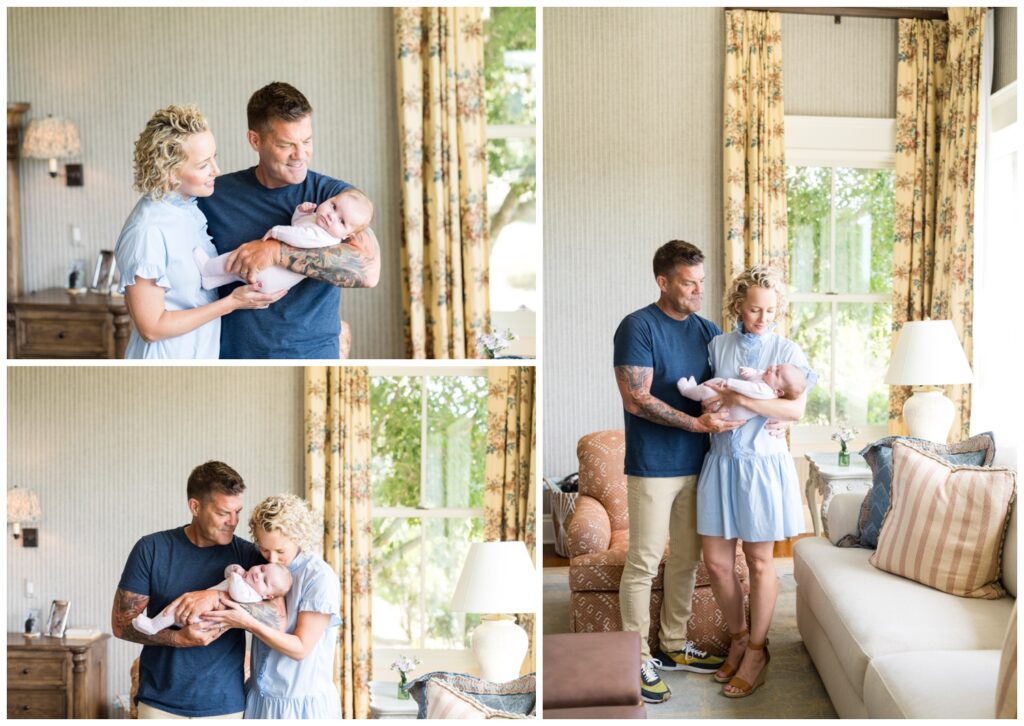 A mother and father standing in their living room, holding their newborn daughter during their photo session.