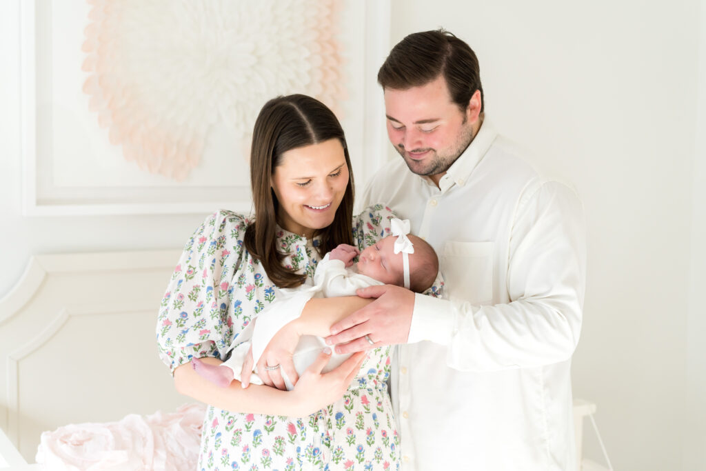 New parents in Austin holding their newborn baby, captured in a bright and candid in-home session.