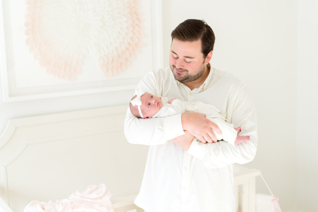 New dad her newborn's forehead during an in-home newborn session in Austin, Texas."