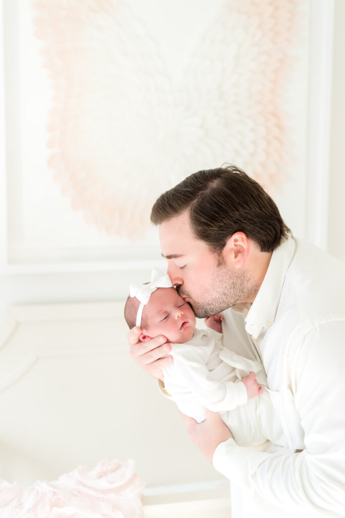 New dad kissing her newborn's forehead during an in-home newborn session in Austin, Texas."