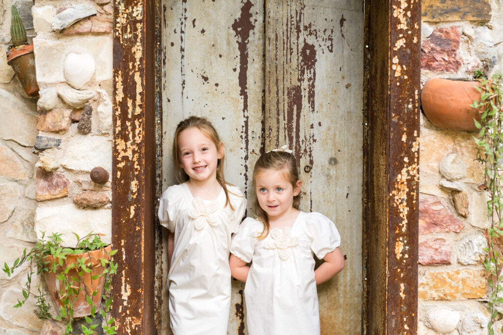 Two young sisters leaning up against an old, rustic door at Sekrit Theater in Austin, Texas.