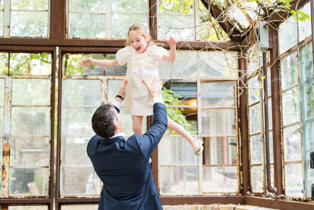 A dad tossing his daughter in the air and catching her as they have family photos taken in Austin, Texas.