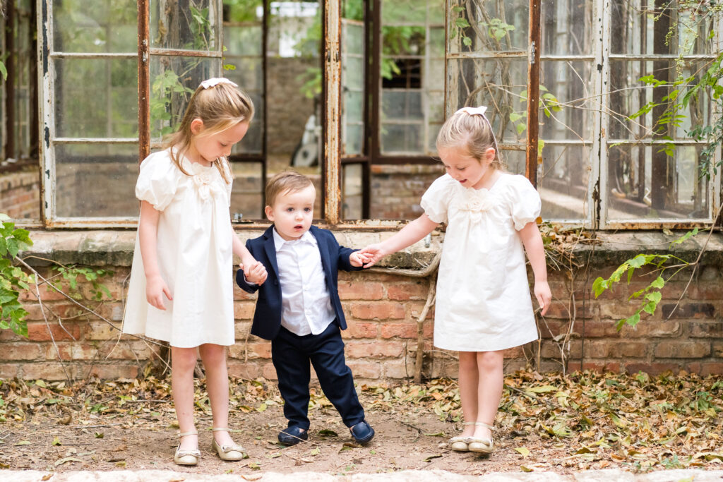 Two young sisters and their little brother holding hands while having their family photos taken by Alissa Cordoba Photography at Sekrit Theater.