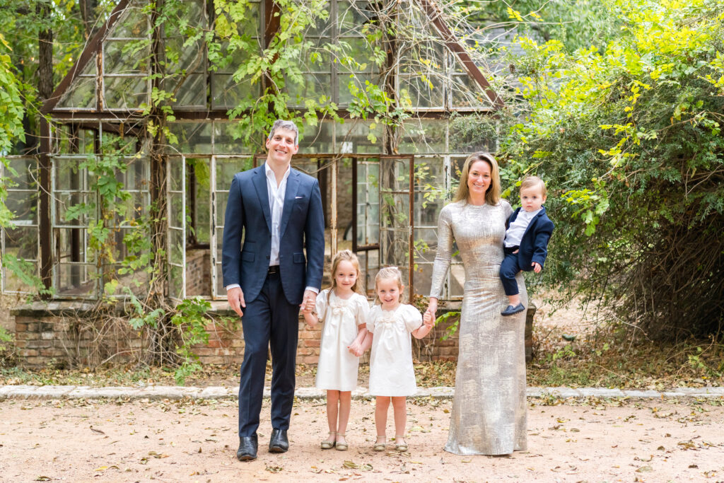 A young family posing in front of the greenhouse located at Sekrit Theater, in Austin.