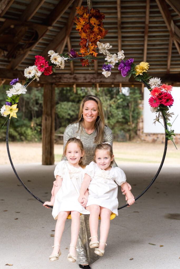 A mom pushing her two daughters on the flower hoop swing at Sekrit Theater.