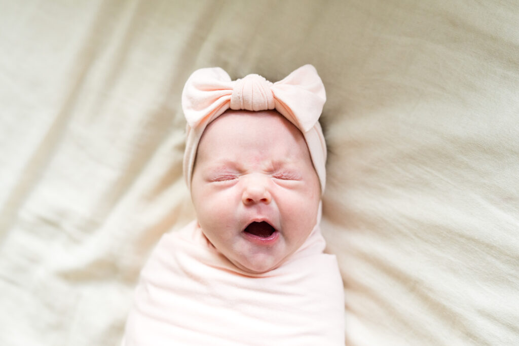 A newborn photo session with a baby girl yawning.