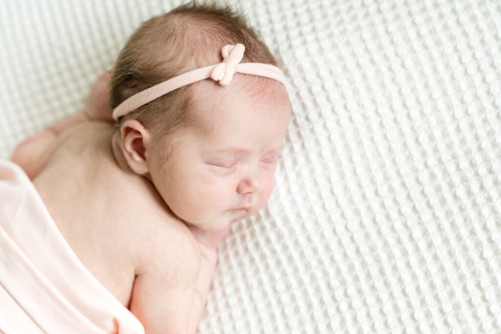 A newborn photo session with a baby girl in a pink blanket
