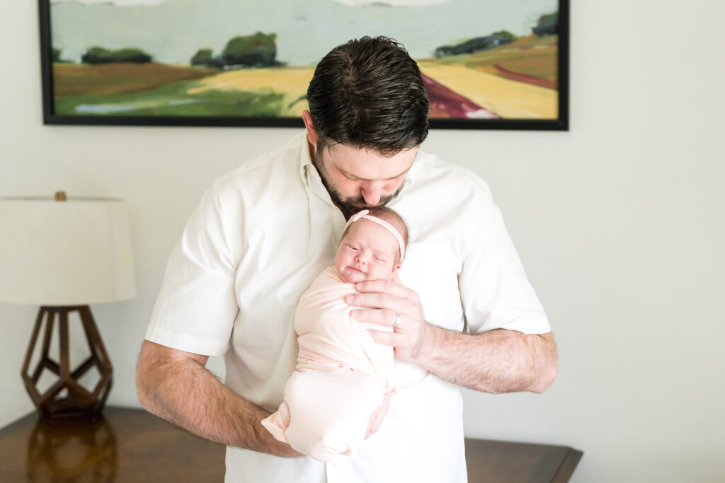 A dad holding his newborn daughter during a photo session with Alissa Cordoba Photography
