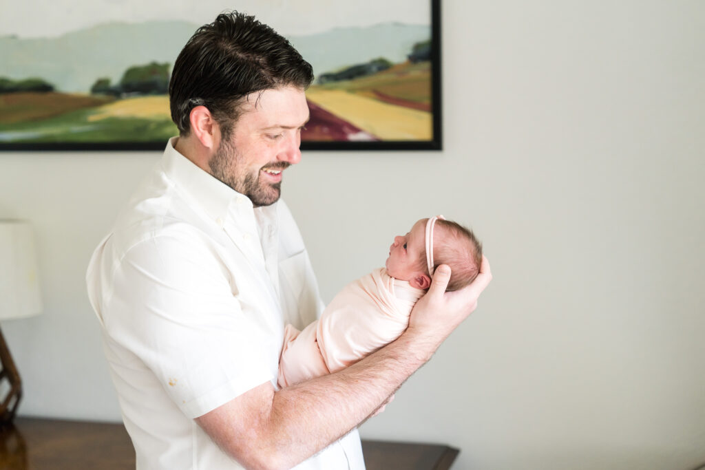 A dad holding his newborn daughter during a photo session with Alissa Cordoba Photography