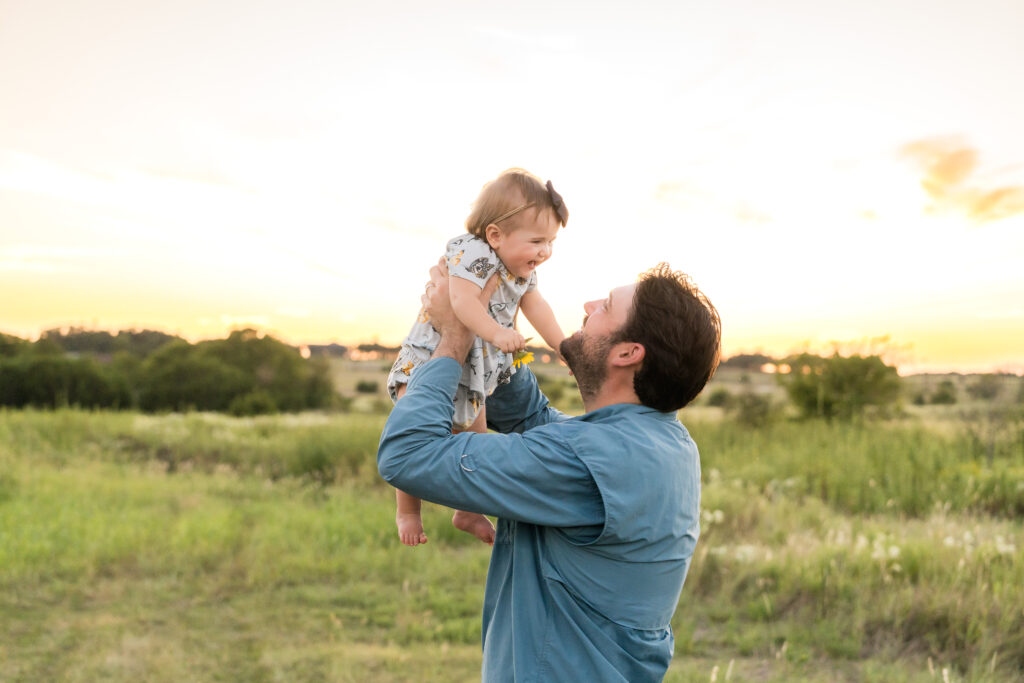 A dad holding his one year old daughter during a sunset photo session.