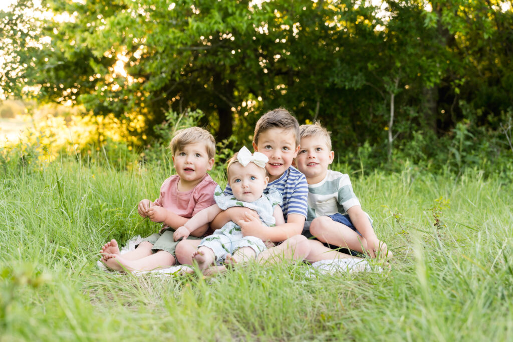 A 6 month old girl with her 3 older brothers during a family photo session.
