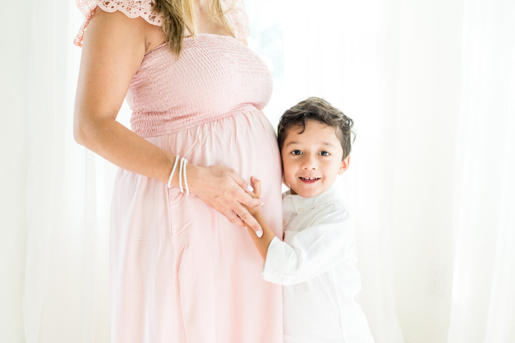 Mother smiling with young son during light-filled maternity family photo session by Austin family photographer, Alissa Cordoba.
