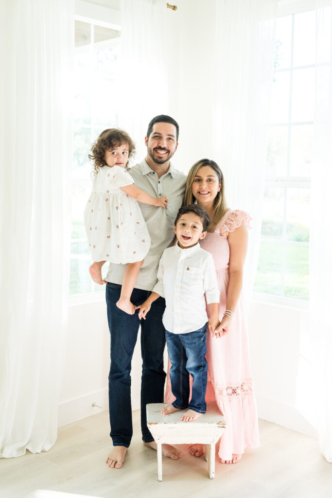 Family of four embracing during relaxed maternity family photo session in Austin, Texas
