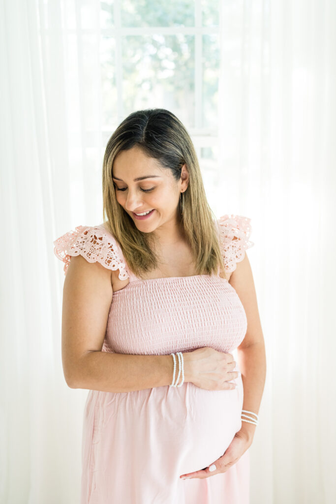 Pregnant mother in pink dress during natural light yearly family photo session in Austin, Texas
