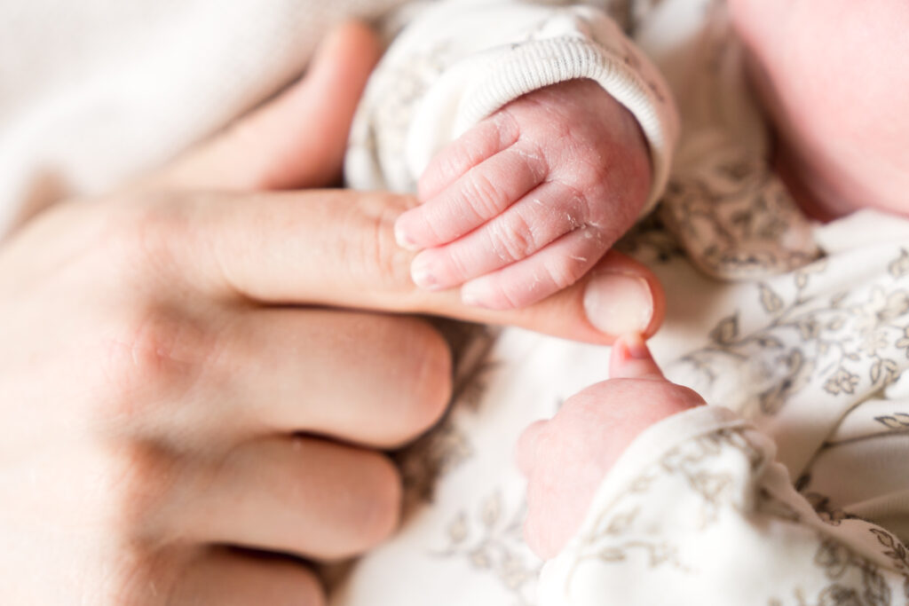 A newborn holding onto her dad's finger.