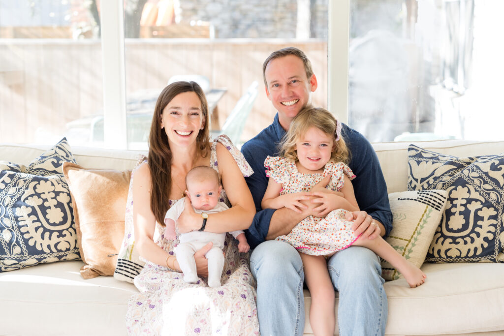 A family sitting on a window bench for their portraits in their Austin city home.