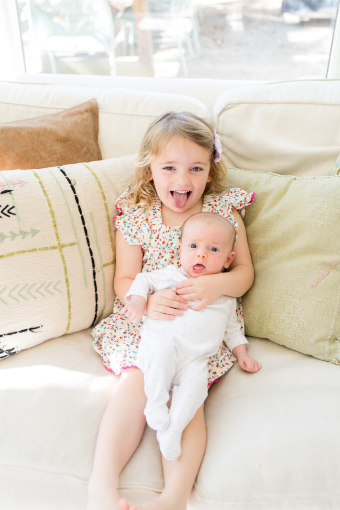 A big sister holding her new baby sister during their in-home family portraits in Austin.
