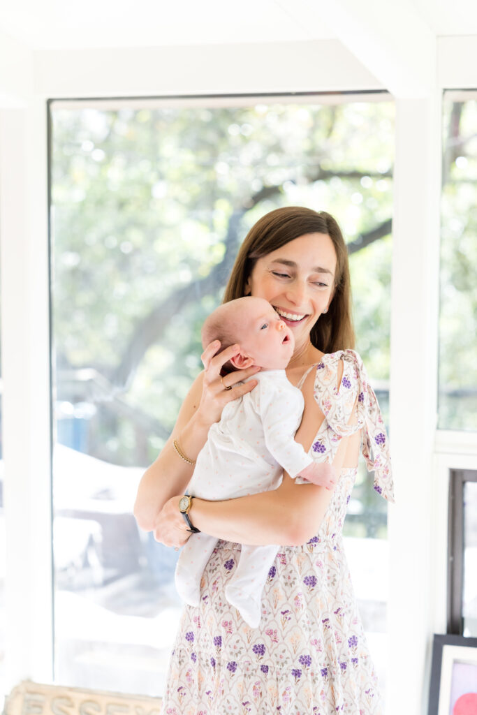 A mom holding her newborn daughter while Austin family photographer, Alissa Cordoba, takes their photo.
