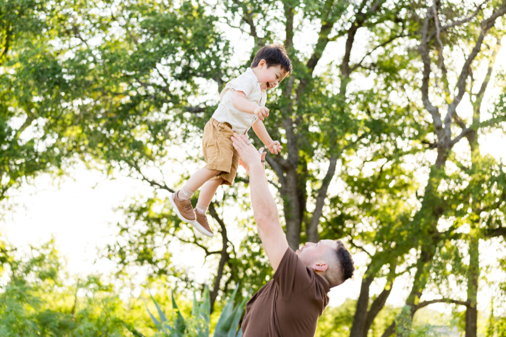 Dad throwing his son in the air during their family photo session 
