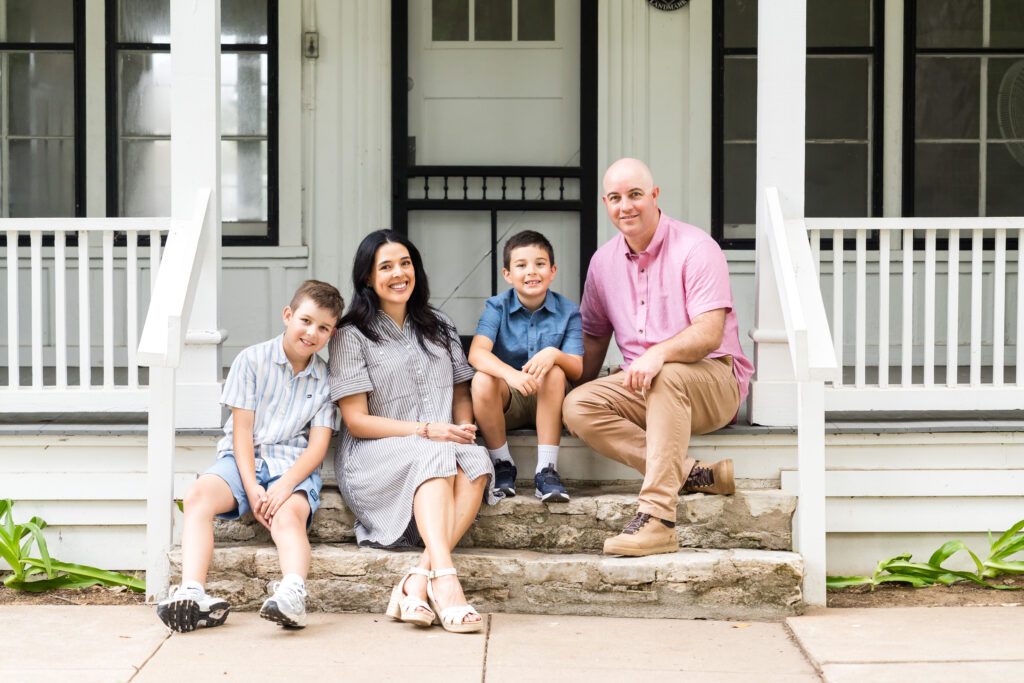 A family posing together on the porch of a house in Austin during their family photo session.